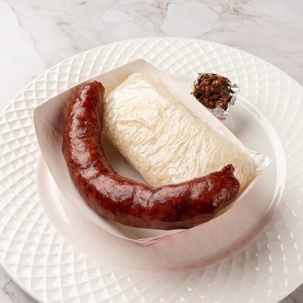 Laos sausage and sticky rice in a paper tray, with a small side of chili paste.