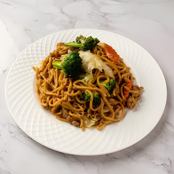 Laos-style stir-fried noodles with broccoli, cabbage, and meat on a white textured plate.