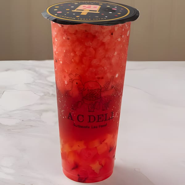 A C Deli's vibrant red fruit smoothie with fruit chunks, topped with a black lid.
