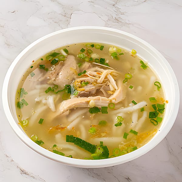 A C Deli's Laos chicken noodle soup with green onions and pepper in a white bowl.