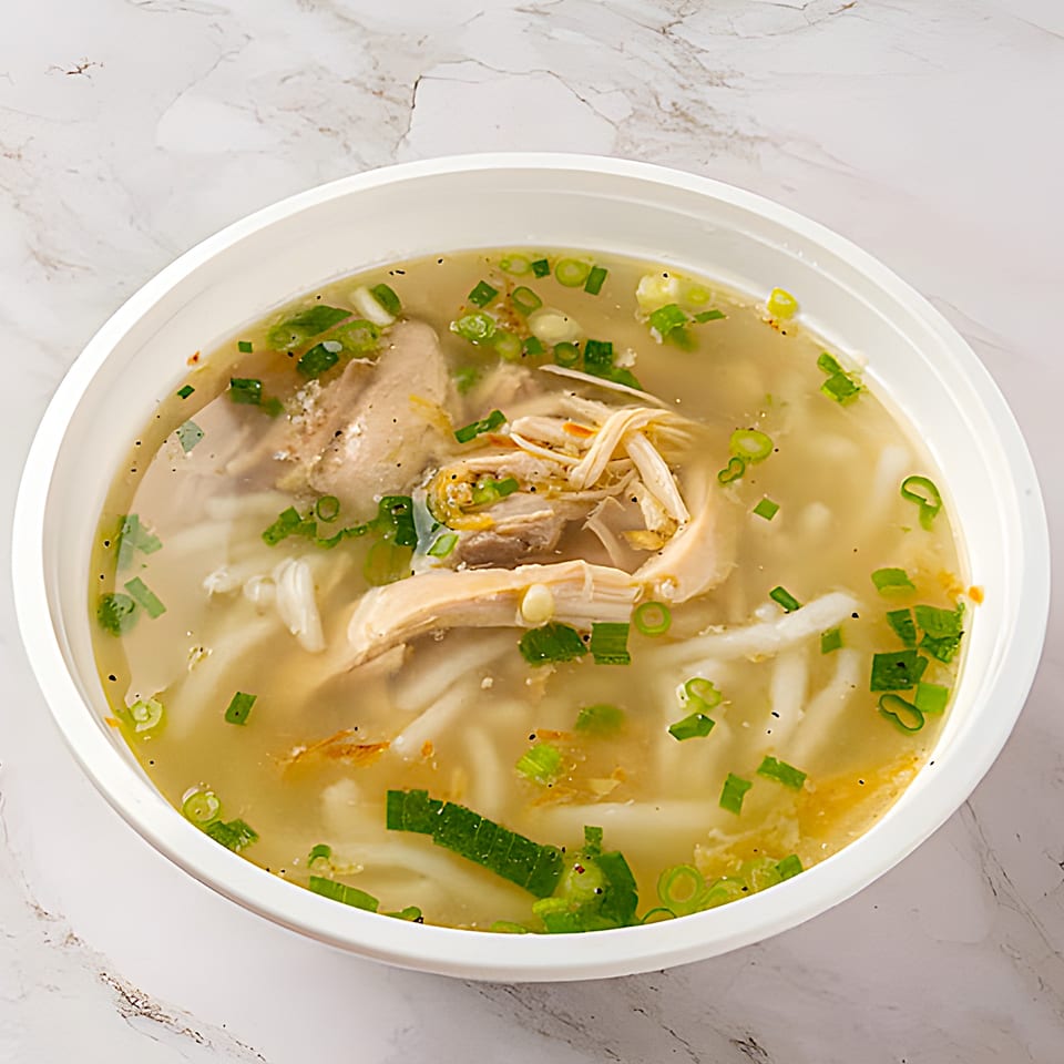 A C Deli's Laos chicken noodle soup with green onions and pepper in a white bowl.