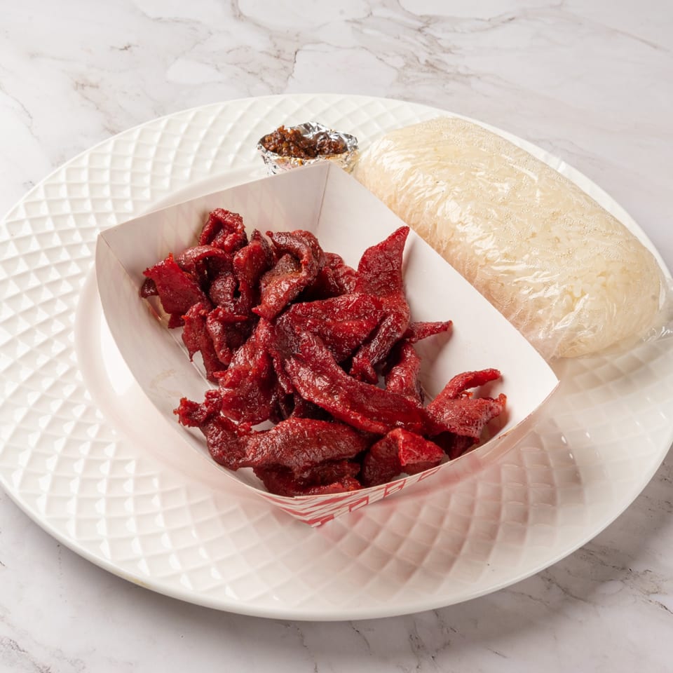 Laos beef jerky in a paper tray, sticky rice, and chili sauce on a white plate.