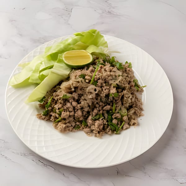 Laos Larb, a minced meat salad with fresh herbs, lime, and cabbage on a white plate.