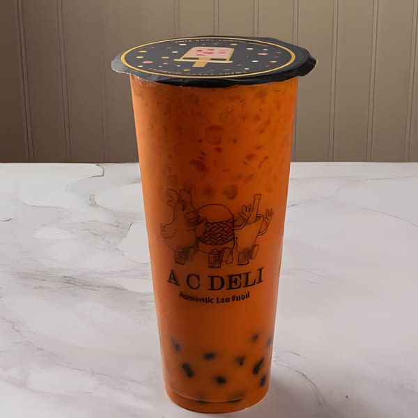 A C Deli's Thai iced tea with tapioca pearls in a clear cup with a black lid.